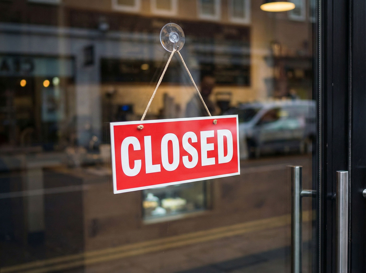 A 'Closed' sign hanging on the inside of a shop window, symbolizing the temporary trading halt covered by business interruption insurance.