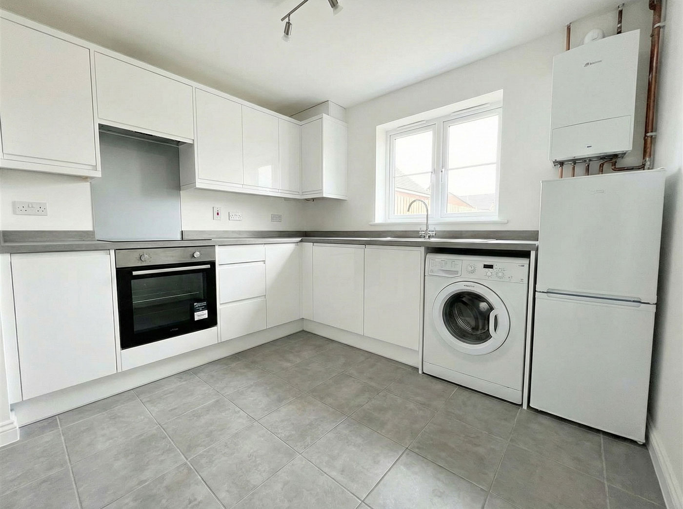 A clean, modern kitchen in a rental property with built-in appliances, a fridge-freezer, and a boiler, representing the landlords' fixtures and fittings protected by landlord insurance.
